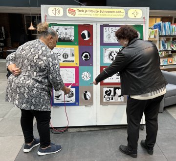 Stoute Schoenen | Stoute Schoenen biedt zinvolle kunstworkshops voor ouderen, gegeven door professionele kunstenaars. De workshops prikkelen, activeren en geven nieuwe energie aan ouderen, waarbij persoonlijke verhalen worden gedeeld en verbeeld in kunstwerken. Tijdens Tilburg on Stage zijn er kunstwerken te zien van de voorjaarscursus 2024. Dit is een gecombineerde cursus van 3 kunstdisciplines namelijk : Textiel, Tekenen (gemengde techniek) en Literatuur & Ontwerp met het thema Passie. Bekijk de expo in de Schouwburg foyer!
