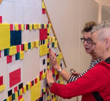 Stichting KIVI – Taktila kleurensysteem| Stichting KIVI exposeert voelreplica’s van kunstwerken, gemaakt met het Taktila kleurensysteem, ontwikkeld door de Tilburgse kunstenaar Jofke van Loon. Dit systeem stelt mensen die geen kleuren of beelden kunnen zien in staat om toch het kleurgebruik, de sfeer, compositie en gelaagdheid van een schilderij te ervaren. Bezoekers met goed zicht worden uitgenodigd een blinddoek om te doen en kunst op de tast te beleven. Ontdek deze unieke replica’s in de foyer van de schouwburg.