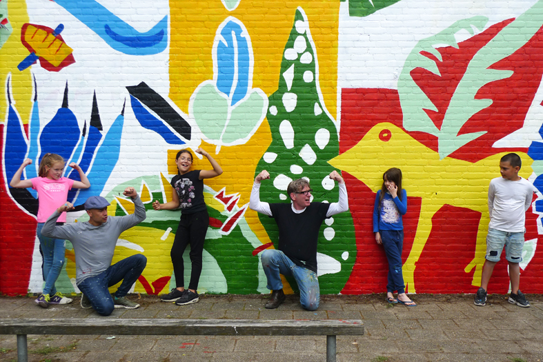 In de periode van de coronamaatregelen nam een leerkracht van VSO Parcours contact op met Art-fact over de muur op hun schoolplein. Art-fact maakte de verbinding met de schilderdames van Koningsvoorde en zo werd het een mooi buurtcultuurproject van. Zowel leerlingen als dames hebben mee helpen ontwerpen én brachten de schilderingen aan.  